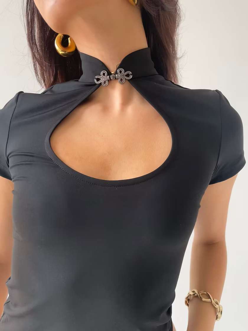 Black top with a unique mandarin collar cut out neckline design with silver hardware on a plain background