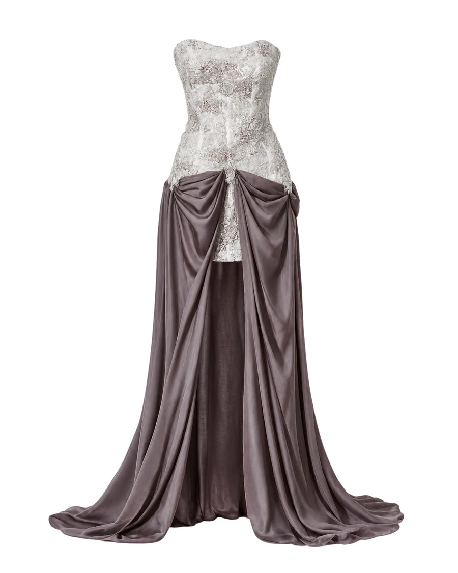 A strapless formal gown displayed on a mannequin against a plain white background. The bodice features a textured, glittering white lace overlay, while the skirt is made of draped satin in a muted  mauve color with a high draped waistline.