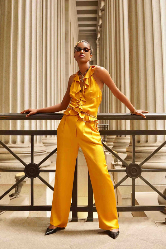 Woman in a yellow outfit standing in front of classical architecture