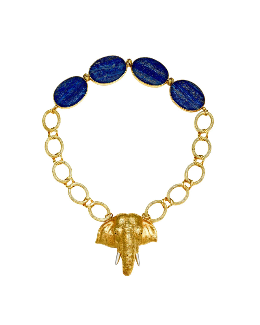 A gold chain necklace featuring five oval dark blue lapis lazuli stones at the top and a textured gold elephant head pendant hanging from the center, set against a plain white background.